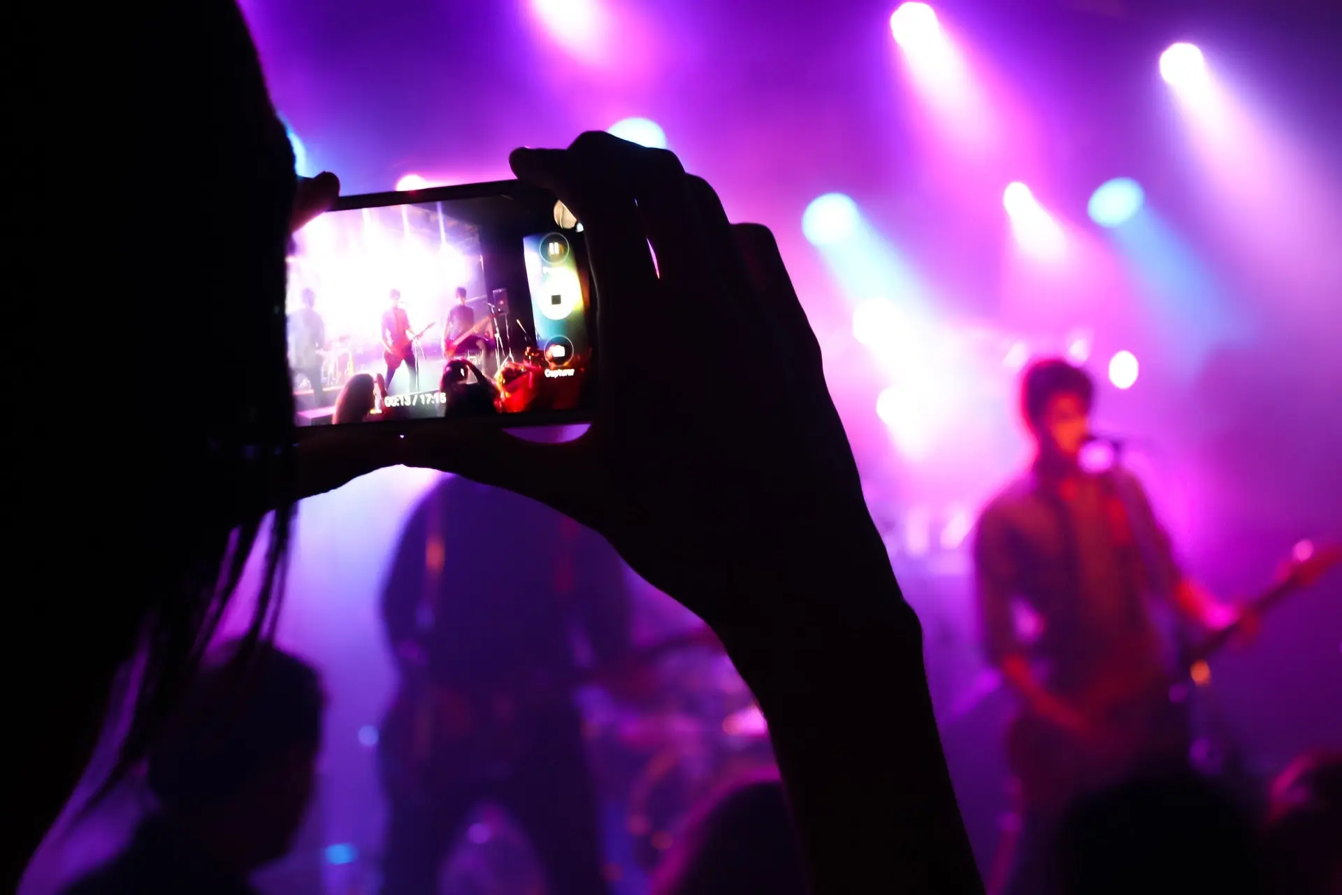 A band performing in a club, someone recording that with a phone